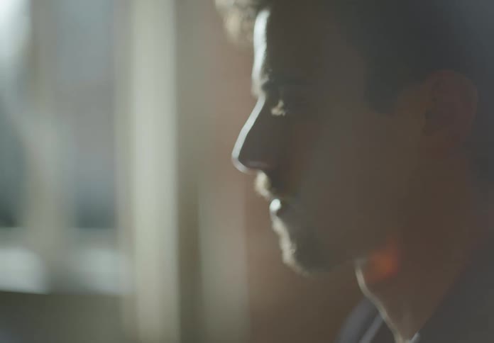 A man blinks a lot as he sits and stares