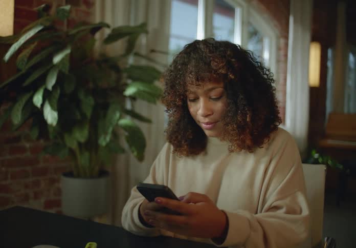 Woman working from home on a computer checking her phone