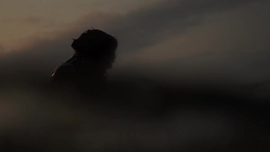 A man paddles on a surfboard near sunset