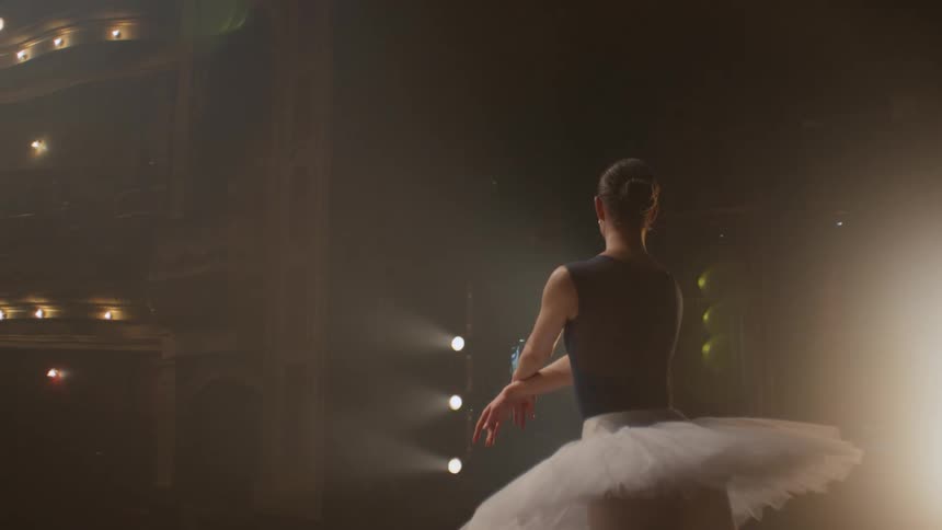 Ballerina dance on stage in dimly lit empty theater