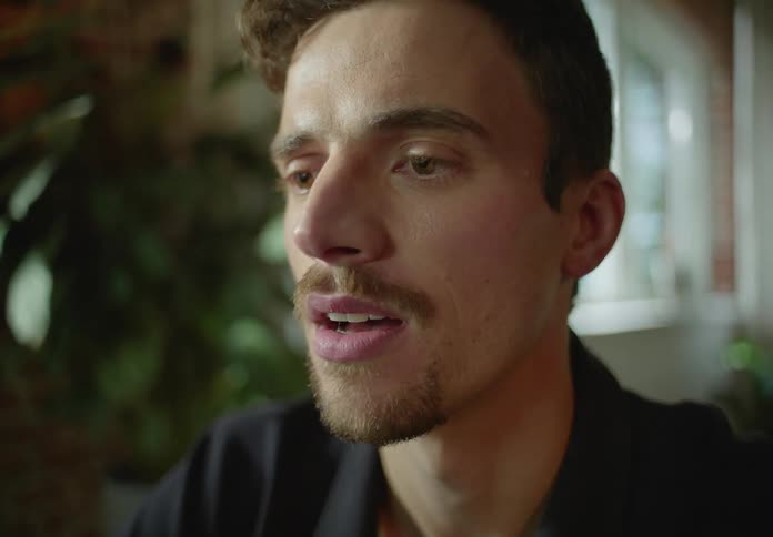 Man with black shirt and goatee makes a video call on laptop smiling in the office