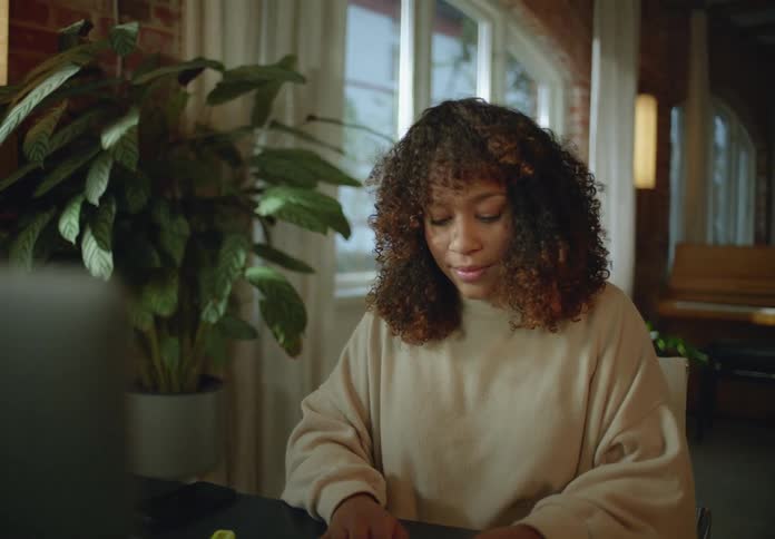 A woman is sitting in front of a computer screen and typing