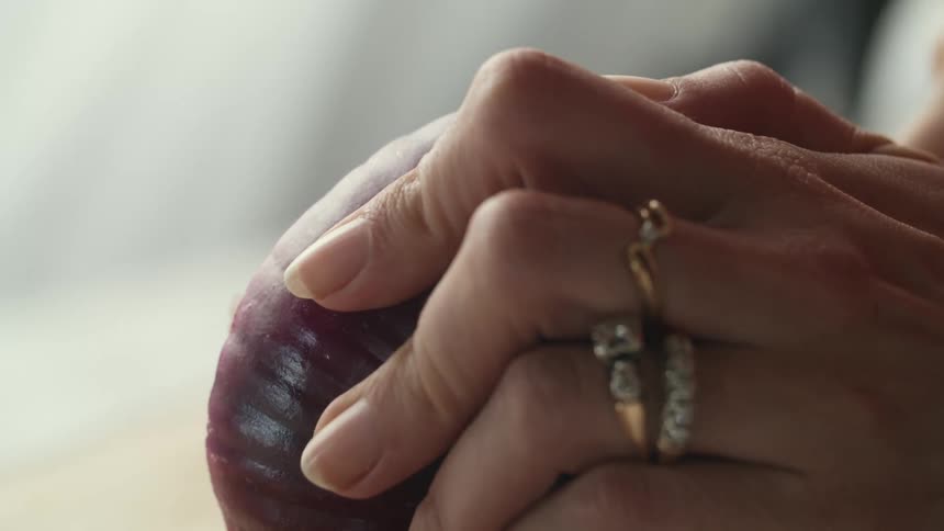 Close up female hands slicing a red onion