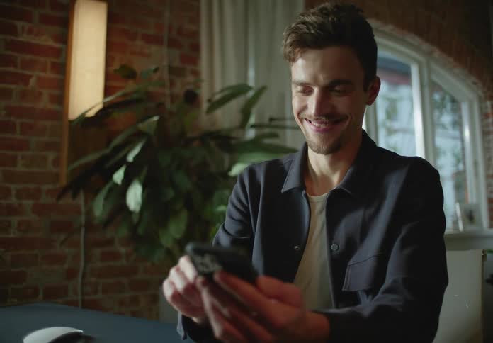 A man is sitting at his desk using a cell phone