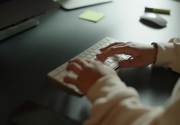 Woman with brown sweater types on computer keyboard
