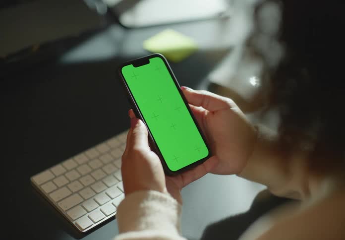 A person is using their cell phone at the desk