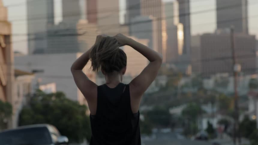 A woman ties her hair as she travels down a street