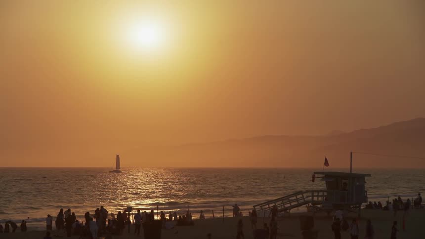 People are all on the beach at sunset