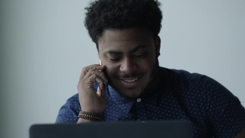 A man in a blue shirt talks on the phone