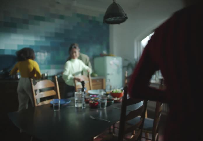 A group of friends bring food to a dinner table