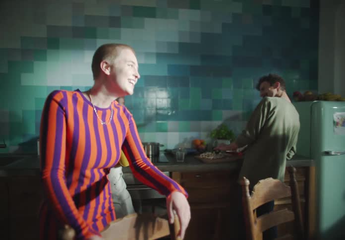 A woman talks as a man cooks at the counter