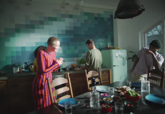 A group of friends standing around in a kitchen