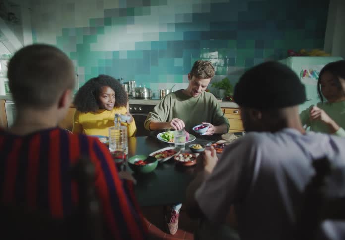 A group of young adults sit around a dining able with food together