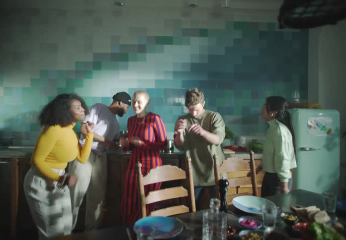 A group of people dance together in a home kitchen during the day