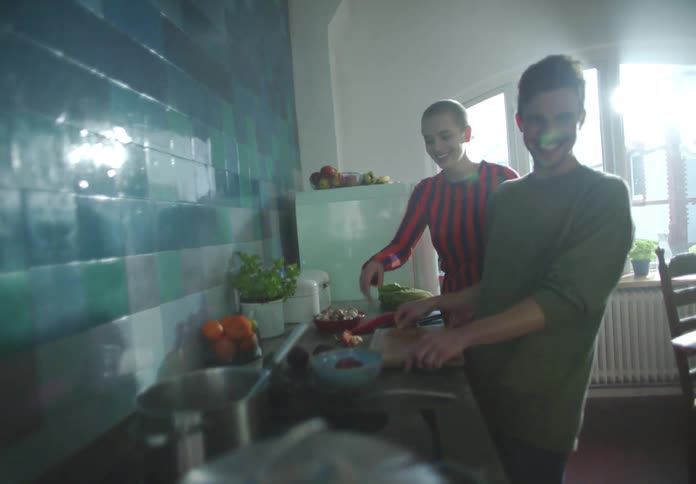 Friends smile and talk while cooking in kitchen together