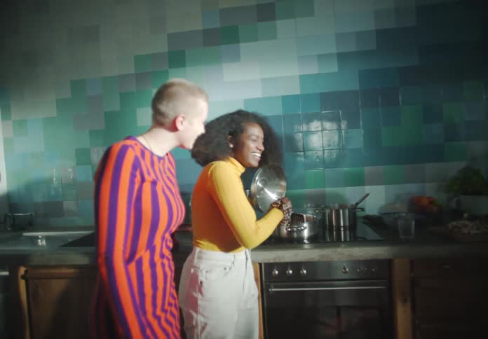 Friends talks and smile as they work in kitchen together