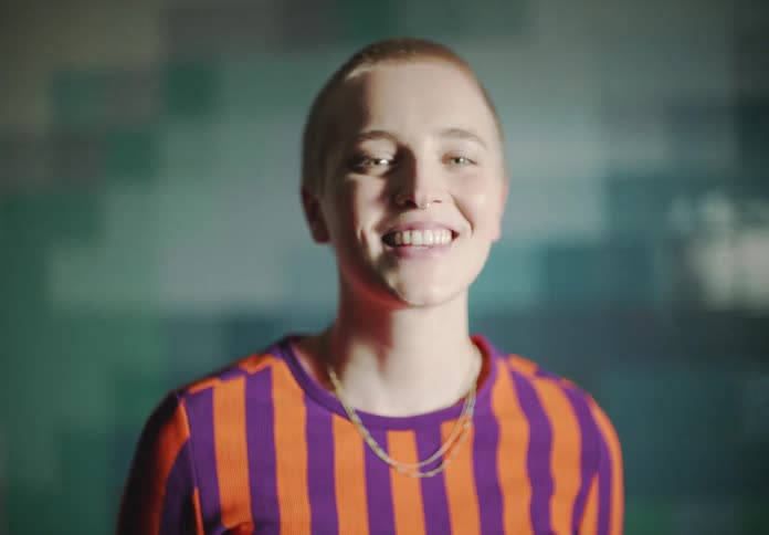 Woman with short hair necklace and striped shirt looks at camera smiling