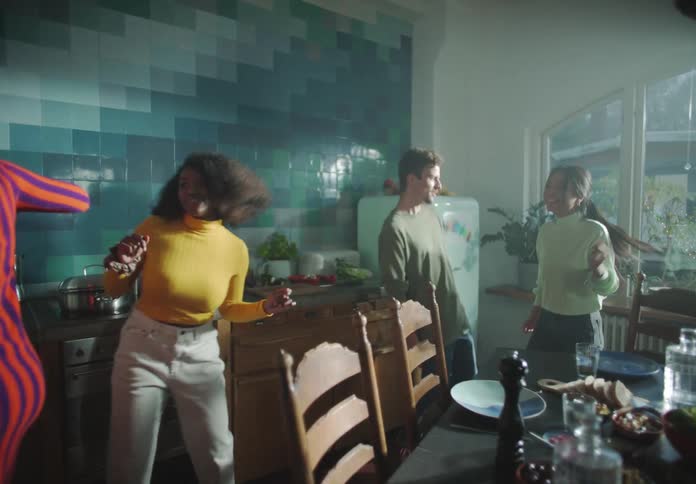 A group of people are laughing and dancing in a kitchen