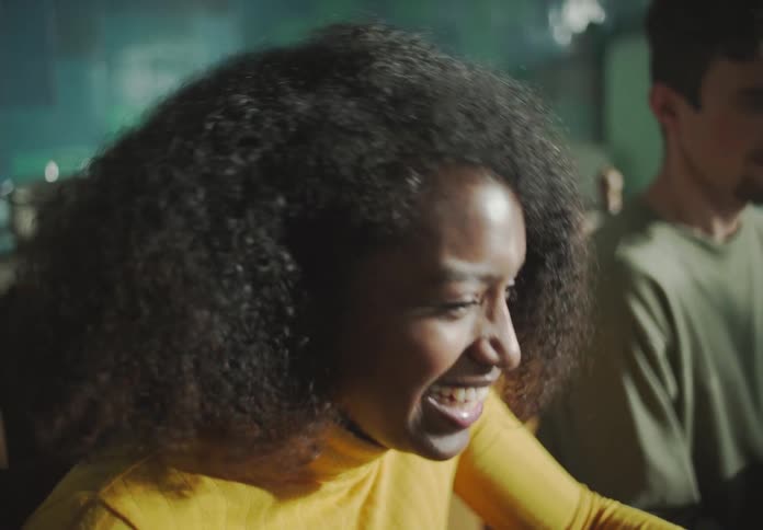 A woman is seated at a table with a man and she is laughing and talking