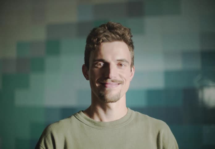 Man with goatee and green sweatshirt faces the camera with eye contact