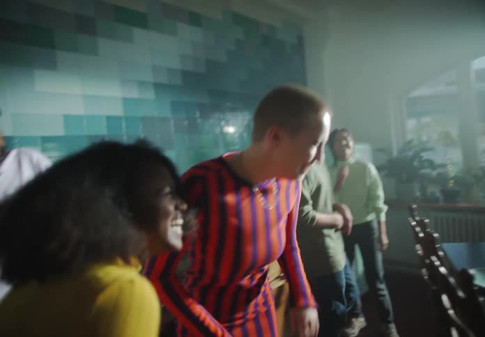 Friends laugh and dance as they gather in a large kitchen