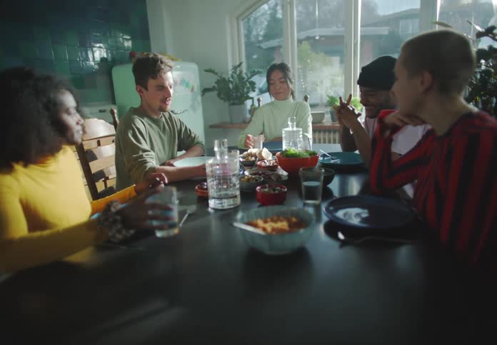 A group of people have a meal together at the dining room table