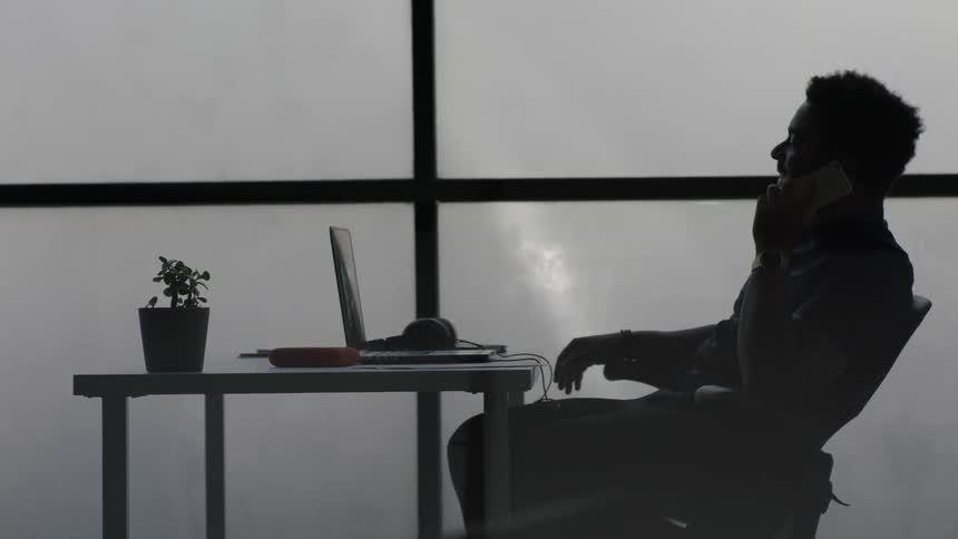 A man is sitting at a table talking on a phone