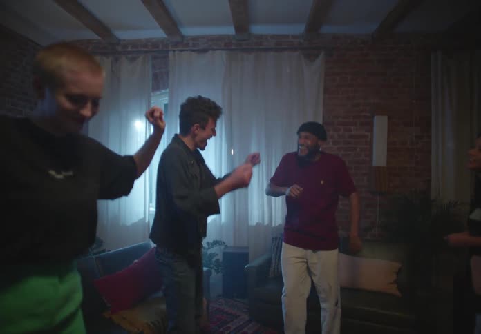 A group of people dance together in the living room of a house during the day