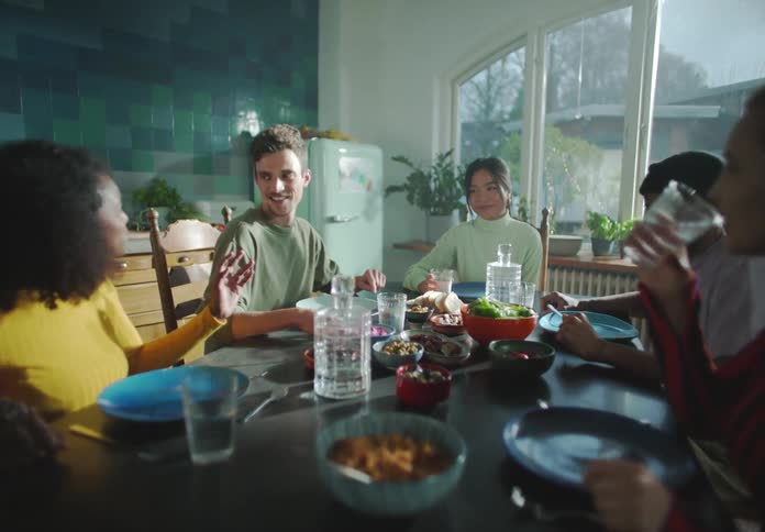 A group of people sit around a table with food and talk