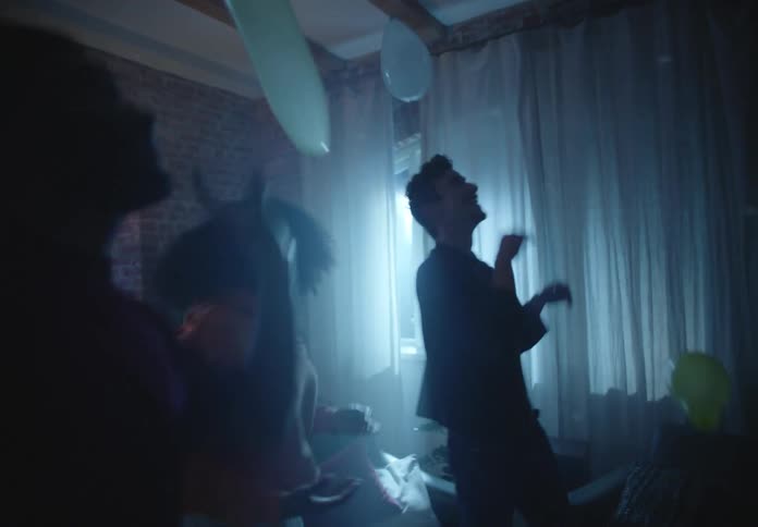 Friends dance in dim room as they play with balloons
