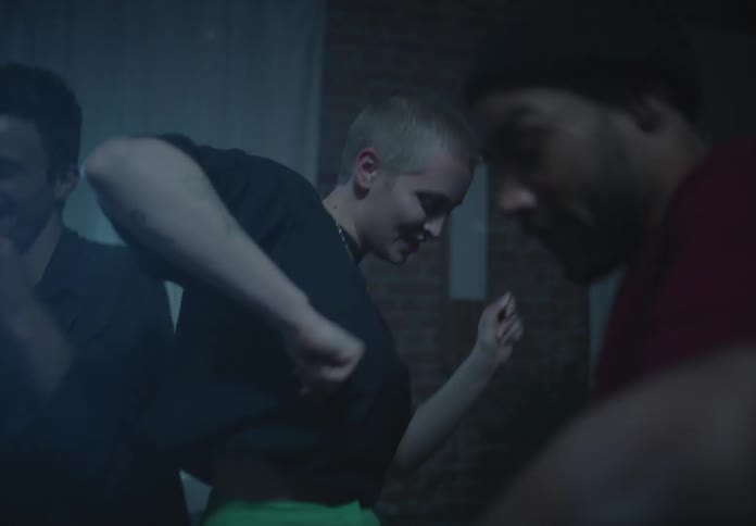A group of teenagers dance in a house with flashing lights