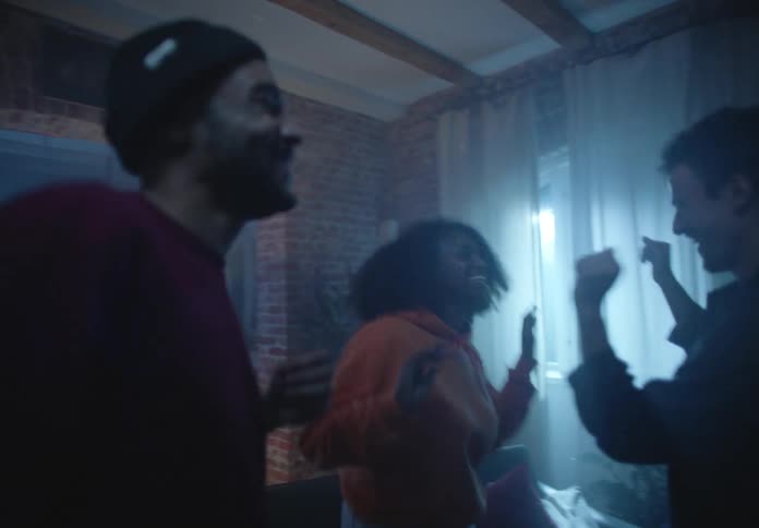 A group of friends dances at a house party with a flashing light