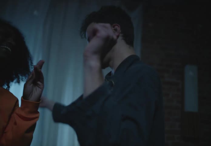A man dances with a woman under flashing lights in a dark room in a house