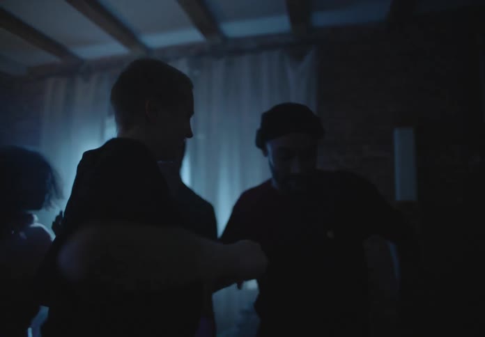People are in a darkened room with flashing lights and dancing