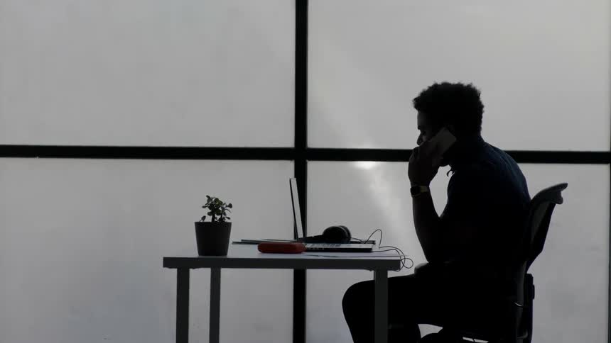 A man talks on a phone and looks around