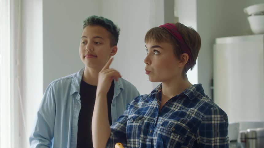 Couple with blue shirts and black top discusses painting the wall in room
