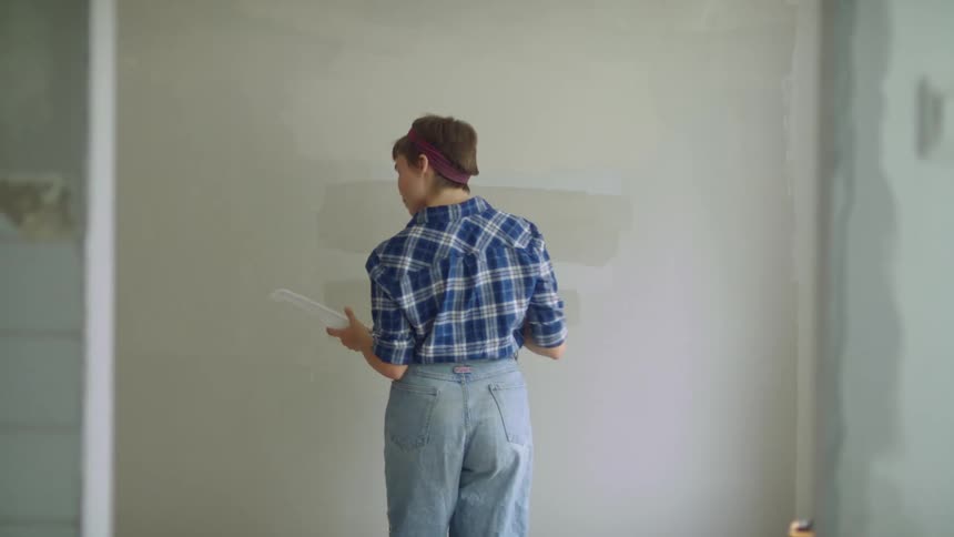 A woman is painting the wall with a roller
