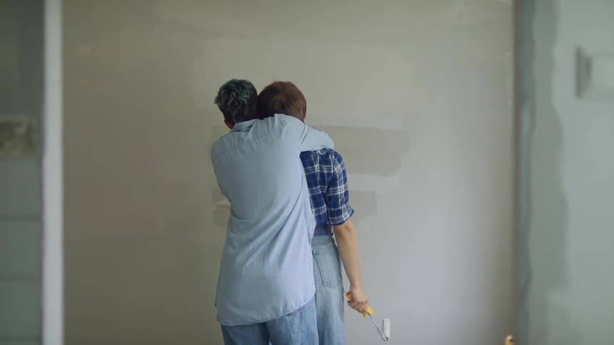 A husband hugging his wife while they paint