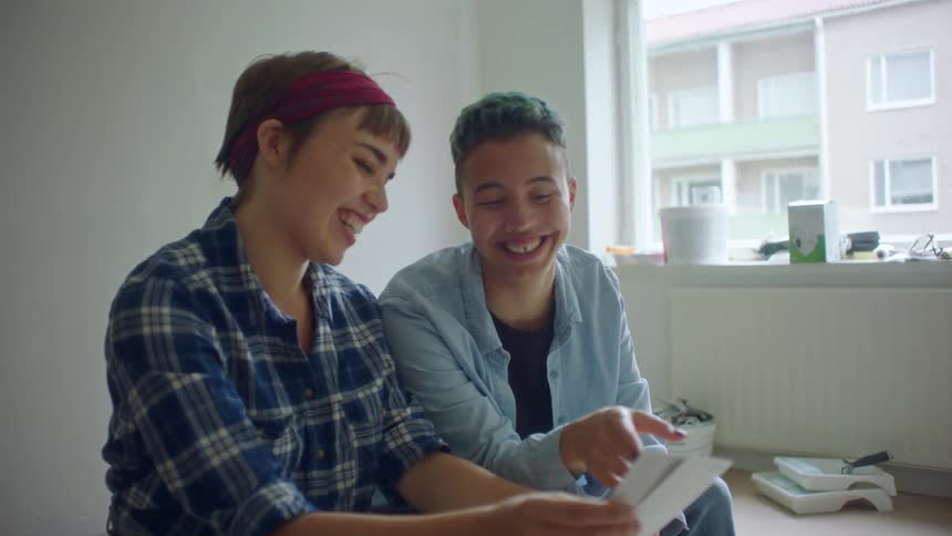 Two friends sits in room contemplating paint samples