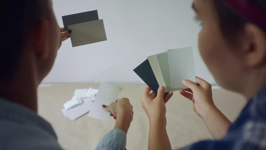 Two women holding paint swatches deciding on color