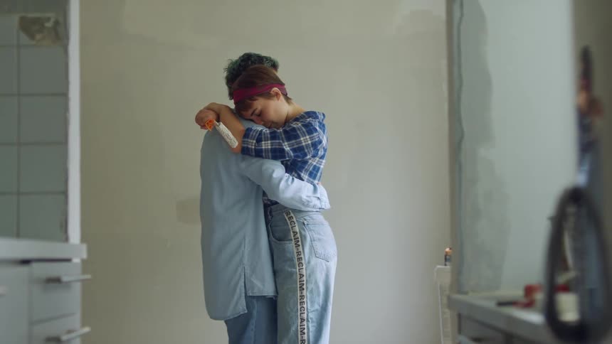 A man and woman hug and dance in the bathroom