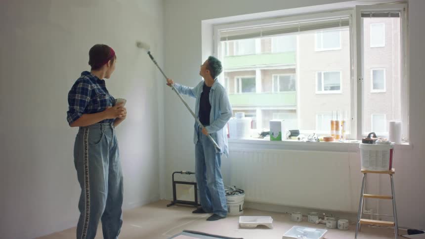 A person uses a paint roller to paint the wall of a home