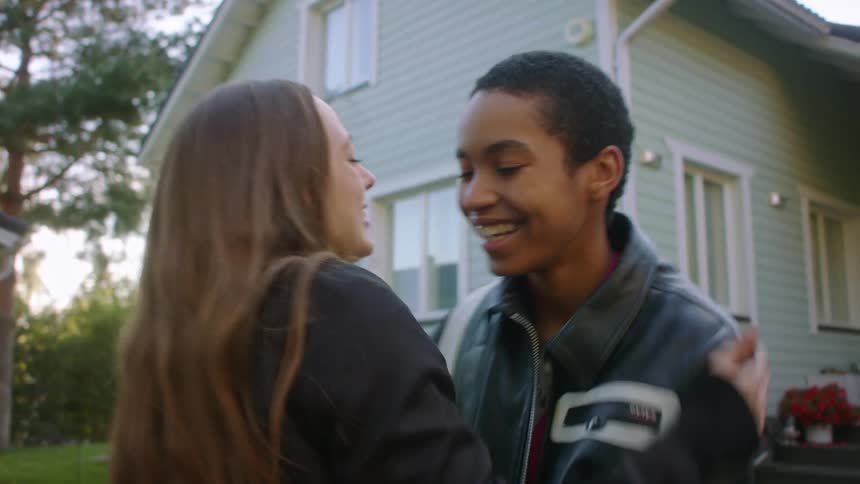 Woman runs down porch steps to greet visiting friend with a hug