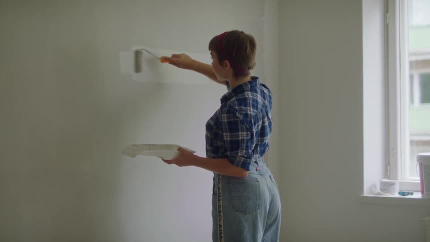 A woman paints a wall in a home