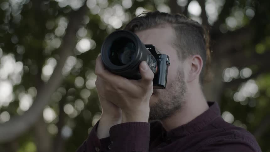 A man lifts his camera to take a photograph