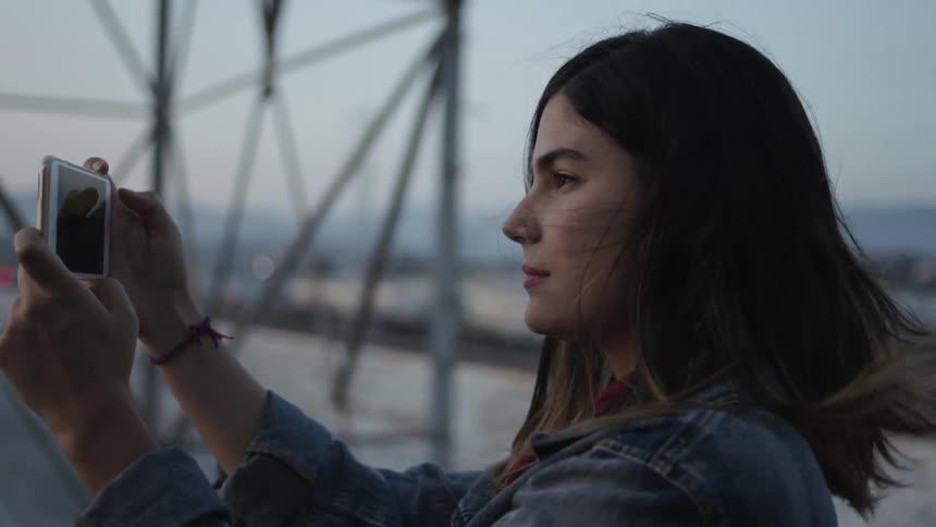 A woman takes pictures with her phone on a windy day