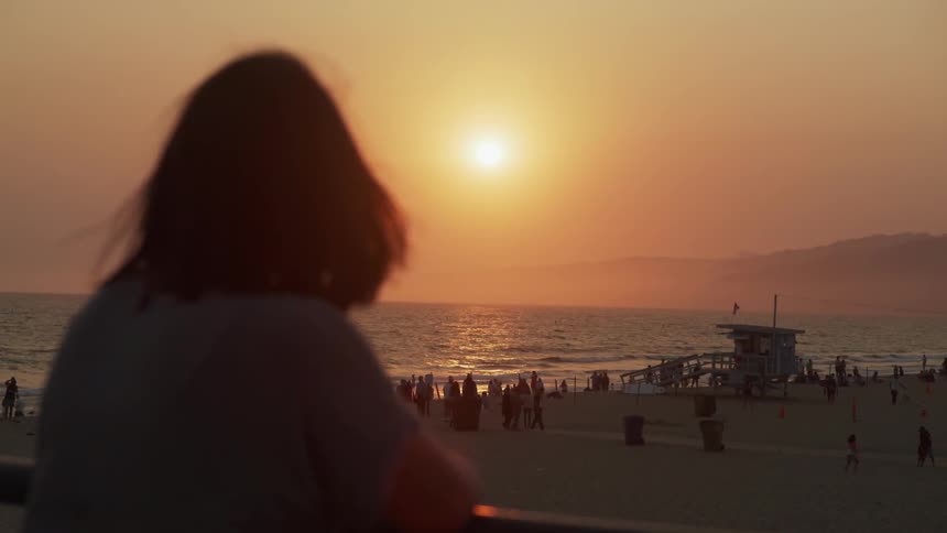 A woman watches the sunset on a beach