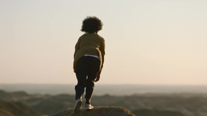 Black woman walks in desert at dusk