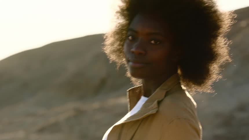 Young woman in the desert turns around to look at the camera