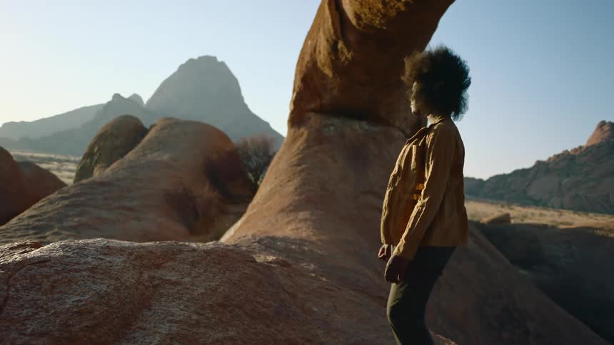 Woman moves near red rock outcropping with misty mountain in background